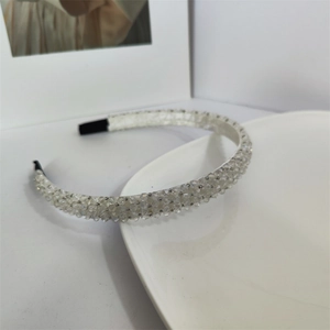 Gros plan des perles de cristal blanc et de la texture satinée du bandeau élégant