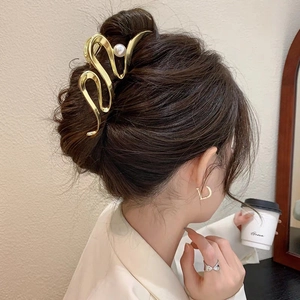 Pince à cheveux dorée en forme de S avec perle blanche sur les cheveux