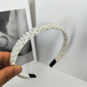 Détail du serre-tête en tissu blanc avec perles de cristal étincelantes et embout noir