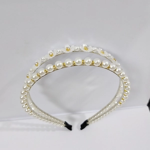 Close-up of double-row pearl headband with white floral accents and small rhinestones