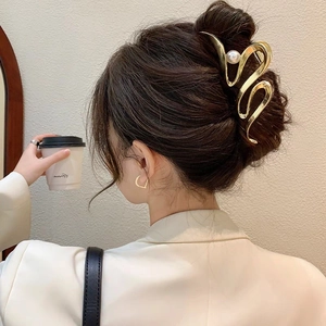 Détail d'une pince à cheveux en métal doré avec perles blanches sur les cheveux