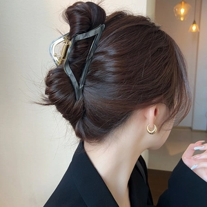 Minimalist black triangular acetate shark clip for hair styling on woman's head