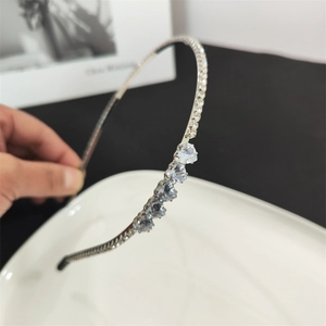 Detail view of a slim silver headband featuring sparkling rhinestones and blue crystal hearts