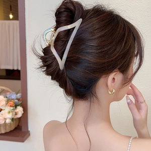Iridescent triangular acetate hair claw clip worn in a messy bun for elegant styling