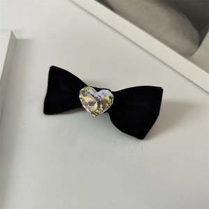 Détail d'une barrette noeud en velours noir avec un centre en cristal étincelant en coeur