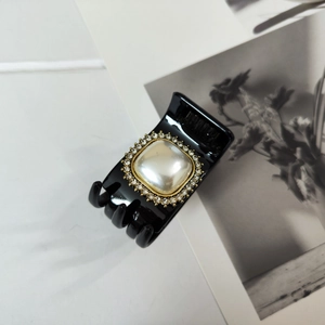 Detailed macro view of a vintage black pearl hair clip with sparkling rhinestone inlay