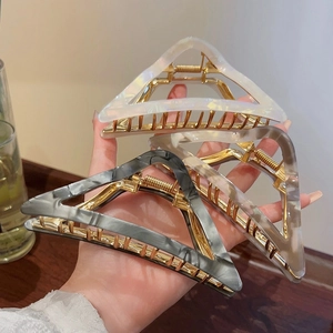 Detail of triangle acetate hair claws with gold frames in white, champagne, and gray ink