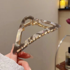 Close-up of marble pattern acetate triangle hair claw clip with golden metal spring