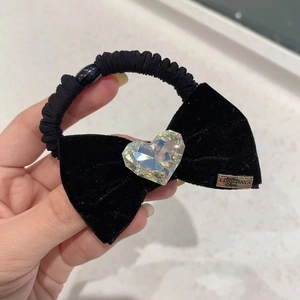 Détail d'un chouchou en velours noir avec un grand cristal de cœur et plaque métal