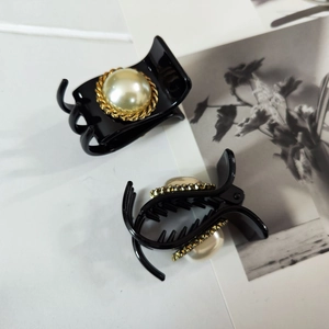 Detail of elegant black hair clips with large pearl and gold braided trim set of two