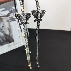 Dettaglio delle nappe argentate e della farfalla di strass sul cerchietto nero