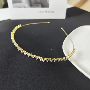 Elegant gold thin headband with wavy cubic zirconia stones on black leather background