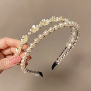 Handheld shot of two elegant Korean-style pearl hairbands with white floral details