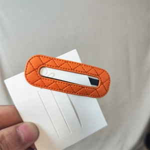 Detail of an orange rectangular PU leather hair clip with diamond quilted stitching
