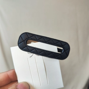 Detailed view of a black oval PU leather hair clip featuring elegant quilted rhombus patterns