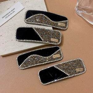 Detail view of black velvet hair clips with sparkling rhinestones and gold LOVEDAYS plate