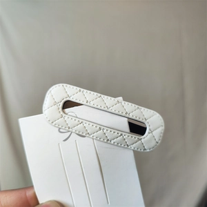 Close-up of white quilted PU leather hair clip with diamond stitching on card