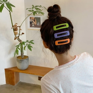 Trois pinces à cheveux en cuir PU coloré vert, violet et orange sur une coiffure élégante
