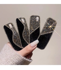 Detailed macro view of black velvet hair clip with luxury rhinestones and LOVEDAYS metal tag