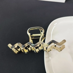 Detail view of the golden metal wavy hair claw clip with tortoise shell pattern texture