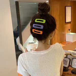 Trois barrettes rectangulaires mates colorées portées par un modèle dans un café