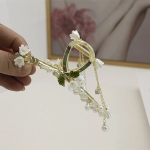 Détail de la pince à cheveux muguet avec feuilles dorées et pompons de perles