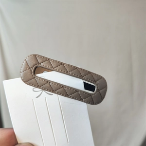 Macro detail of beige PU leather barrette featuring quilted stitching on a metal clip