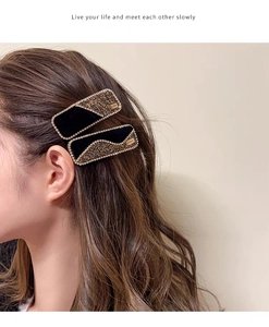 Detail showing two black velvet hair clips with sparkling rhinestones and gold metal tags