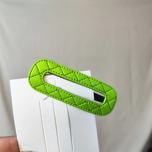 Close-up of bright green quilted PU leather oval hair clip on a display card