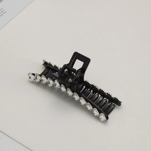 Close-up of black hair claw clip with heart shaped crystals and metal spring mechanism