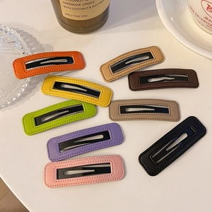 Détail de barrettes BB en similicuir coloré avec coutures nettes et finition mate élégante