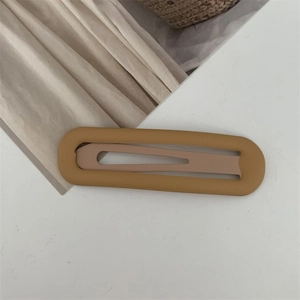Details von mattem ingwergelbem hohlem ovalem Haarclip auf weißem Untergrund