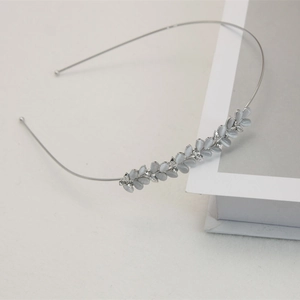Detailed view of silver hairband with cat eye stones and rhinestones in leaf shapes