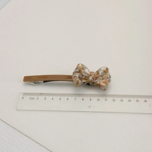 Vue macro d'une pince à cheveux de 11,5 cm en acétate ambré avec règle de mesure