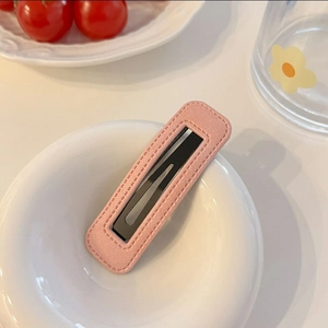 Détail d'une pince à cheveux en cuir PU rose matelassé sur une assiette blanche