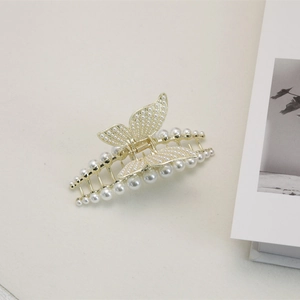 Détail de la pince à cheveux papillon dorée avec perles blanches et ressort