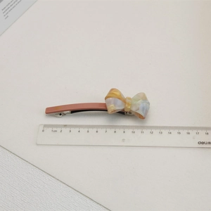 Vue détaillée d'une pince à cheveux nœud en acétate de 8 cm avec texture nacrée