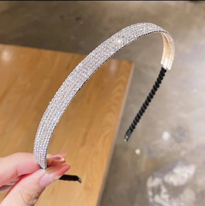 Serre-tête argenté scintillant avec quatre rangées de strass tenu à la main sur bois