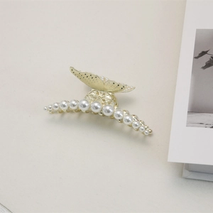 Pince à cheveux queue de poisson dorée avec perles dégradées sur fond minimaliste