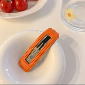 Détail de la pince à cheveux en cuir PU orange avec couture faite main et base métal