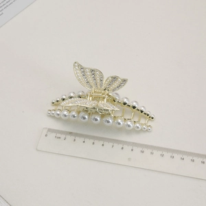 Détail d'une pince à cheveux papillon dorée de 9 cm avec perles et strass