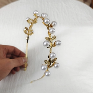Close-up of elegant gold alloy headband with white pearls and delicate metal leaves