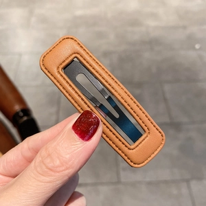 Vue détaillée d'une pince à cheveux rectangulaire en cuir marron avec clip en métal noir