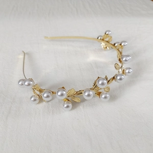 Detailed macro view of golden alloy leaf crown with elegant white pearls and metal foliage