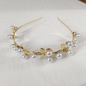 Close-up of golden leaf headband with white pearls and delicate metallic branch details