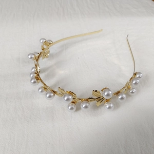 Detailed view of a golden leaf headband with white pearls and vintage metal design