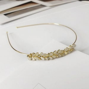Détail d'un serre-tête doré avec feuilles en pierre d'œil de chat et strass brillants