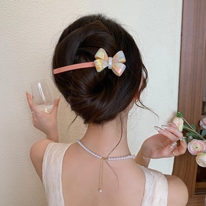 Détail de la pince à cheveux avec nœud en acétate marbré portée par un mannequin