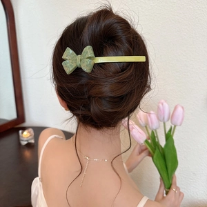 Vue latérale d'une barrette à nœud 3D en acétate vert portée dans une coiffure chic