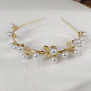 Elegant gold alloy headband with pearl accents and leaf design on a white background